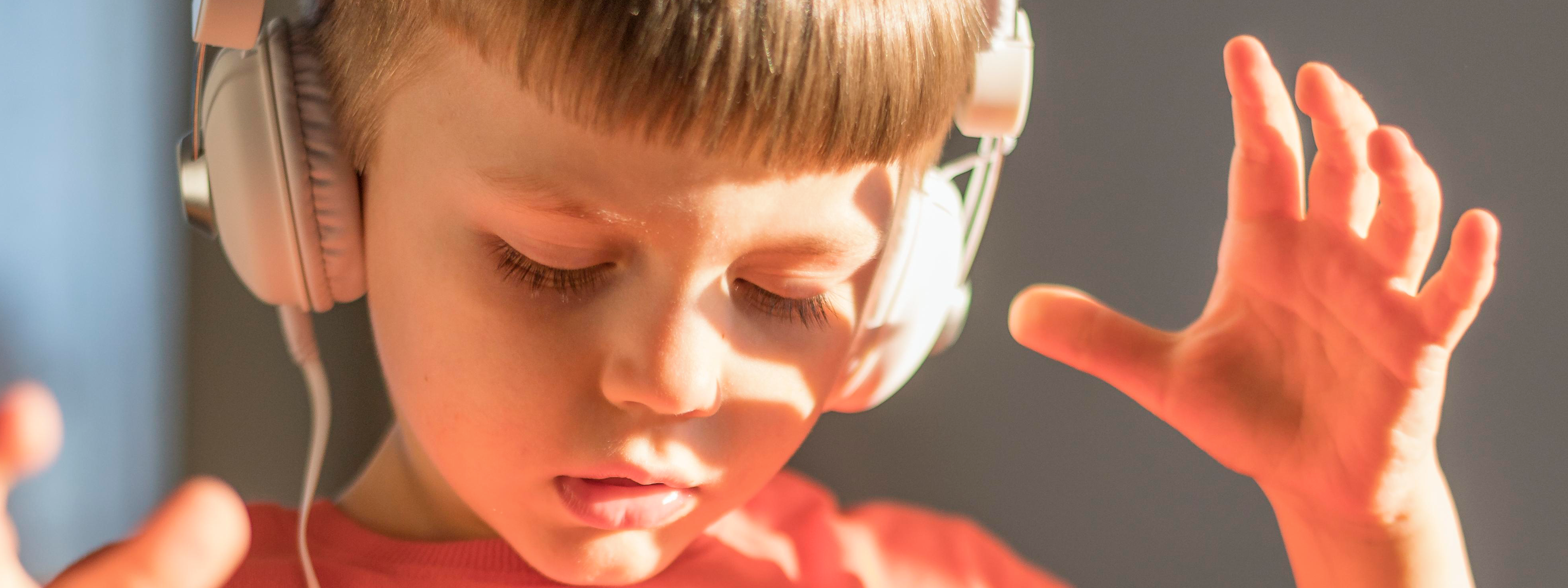 Niño oyendo a través de auriculares